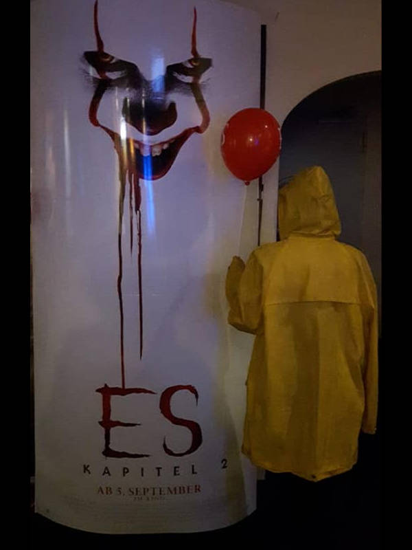 Person im Regenmantel mit Luftballon